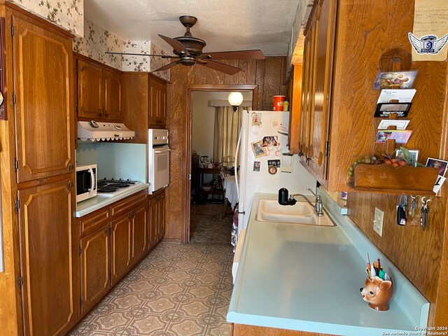 kitchen featuring light tile floors, ceiling fan, a textured ceiling, white appliances, and sink