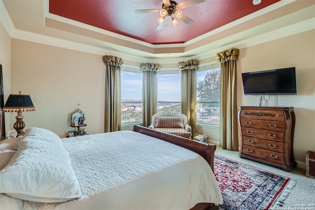 bedroom featuring light carpet, multiple windows, a tray ceiling, and ceiling fan