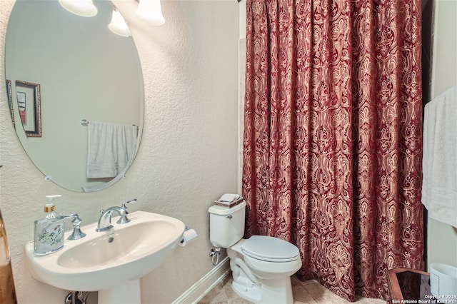 bathroom with toilet, tile floors, and sink