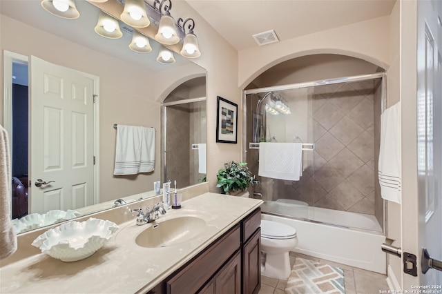 full bathroom featuring vanity, tile floors, toilet, and enclosed tub / shower combo