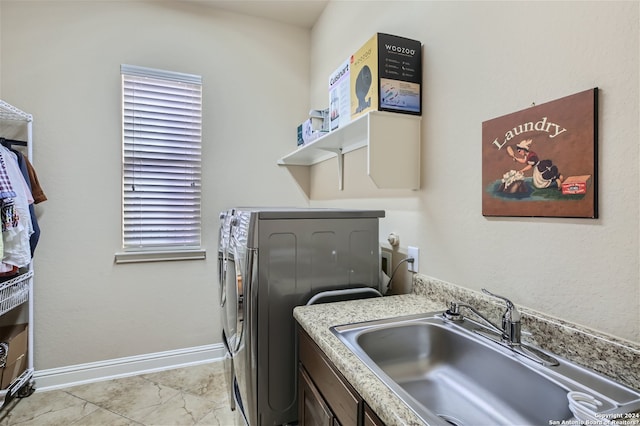 clothes washing area with washer / dryer, light tile floors, and sink