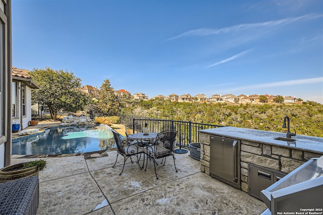 view of patio / terrace with a fenced in pool, pool water feature, and exterior kitchen