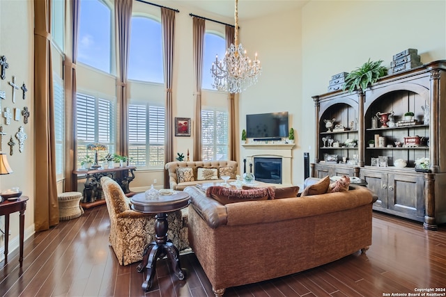 living room with built in features, a notable chandelier, dark hardwood / wood-style floors, and a towering ceiling