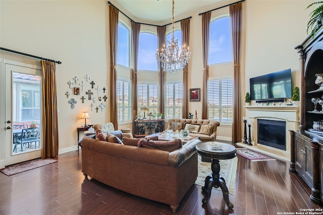 living room with dark hardwood / wood-style floors, a notable chandelier, and a towering ceiling