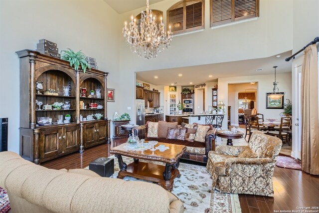 living room featuring a chandelier, a towering ceiling, and dark hardwood / wood-style flooring