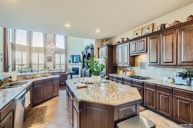 kitchen featuring sink, appliances with stainless steel finishes, tasteful backsplash, a notable chandelier, and a center island