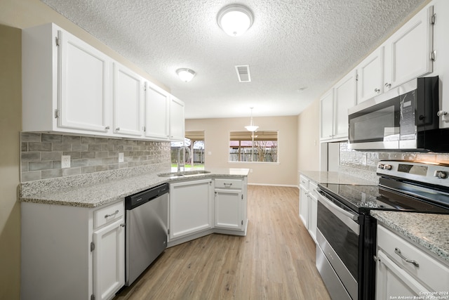 kitchen with white cabinets, sink, appliances with stainless steel finishes, and light hardwood / wood-style flooring