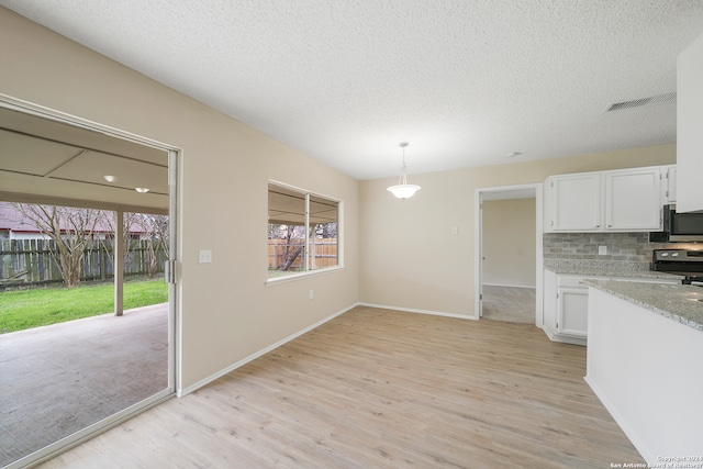 kitchen featuring tasteful backsplash, stainless steel appliances, white cabinetry, and light wood-type flooring