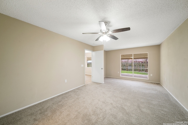 empty room featuring ceiling fan, light colored carpet, and a textured ceiling