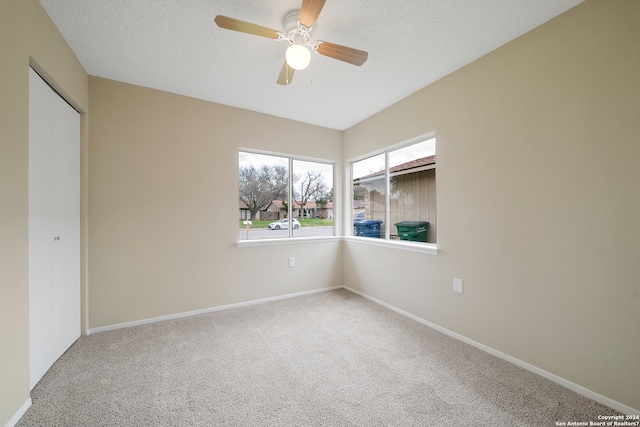 carpeted empty room with a textured ceiling and ceiling fan