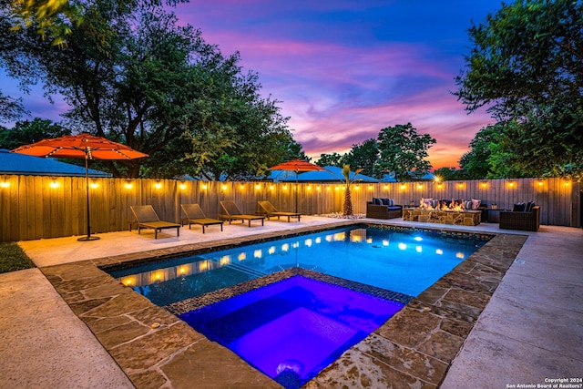 pool at dusk featuring an outdoor hangout area, a patio, and an in ground hot tub