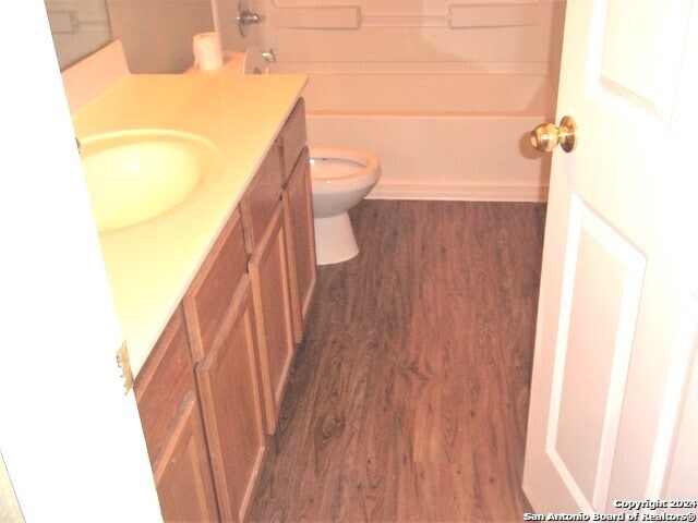 bathroom featuring toilet, vanity with extensive cabinet space, and wood-type flooring