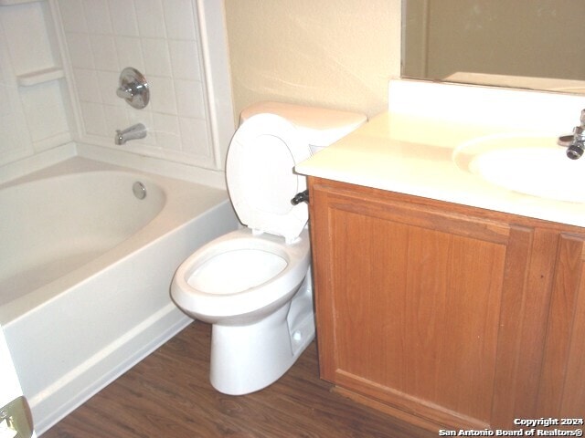 full bathroom featuring toilet, wood-type flooring, vanity, and shower / tub combination