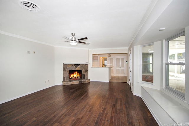 unfurnished living room with ceiling fan, ornamental molding, a stone fireplace, and dark hardwood / wood-style floors