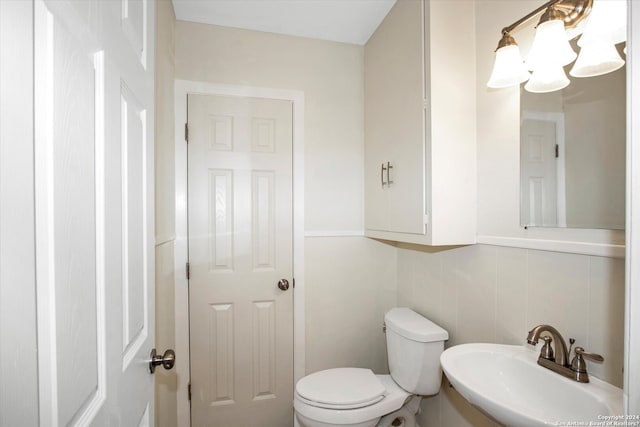 bathroom featuring sink, backsplash, toilet, and tile walls