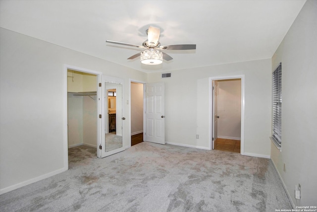 unfurnished bedroom featuring ceiling fan, a spacious closet, light colored carpet, and a closet