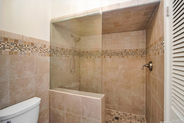 bathroom with tile walls, toilet, and a tile shower