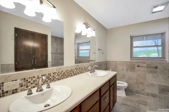 bathroom featuring tile flooring, tasteful backsplash, plenty of natural light, toilet, and dual vanity