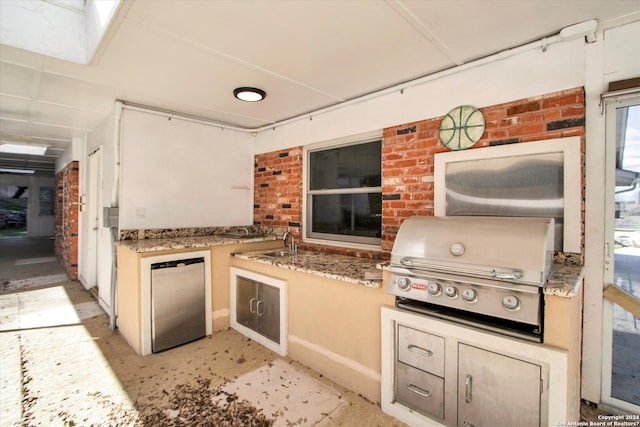 kitchen featuring stone counters, dishwasher, and brick wall