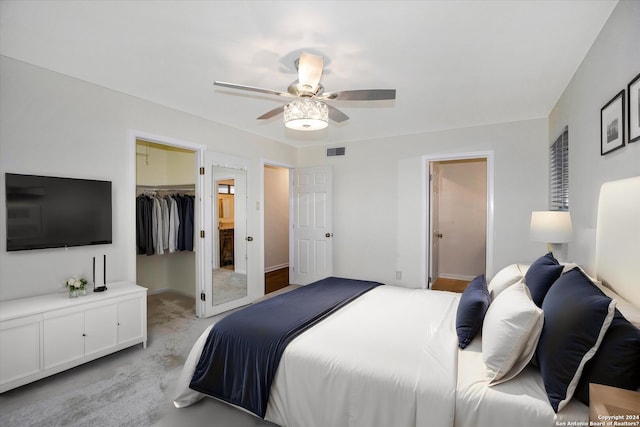 carpeted bedroom with ceiling fan, a spacious closet, and a closet