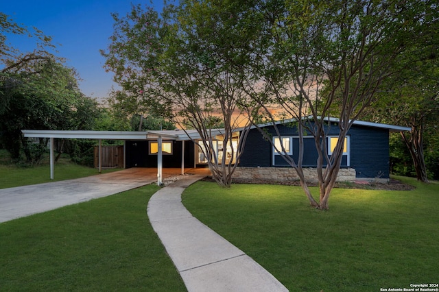 view of front of property featuring a carport and a lawn