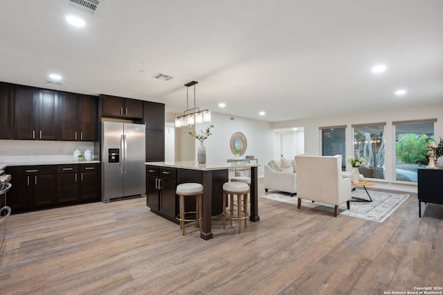 kitchen featuring stainless steel fridge, pendant lighting, light wood-type flooring, and dark brown cabinetry