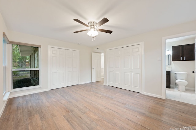 unfurnished bedroom with ceiling fan, light hardwood / wood-style flooring, connected bathroom, and two closets