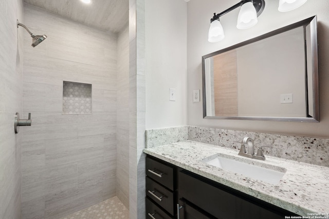 bathroom with a tile shower and vanity