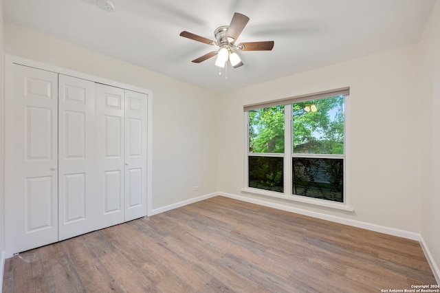 unfurnished bedroom with light hardwood / wood-style flooring, ceiling fan, and a closet