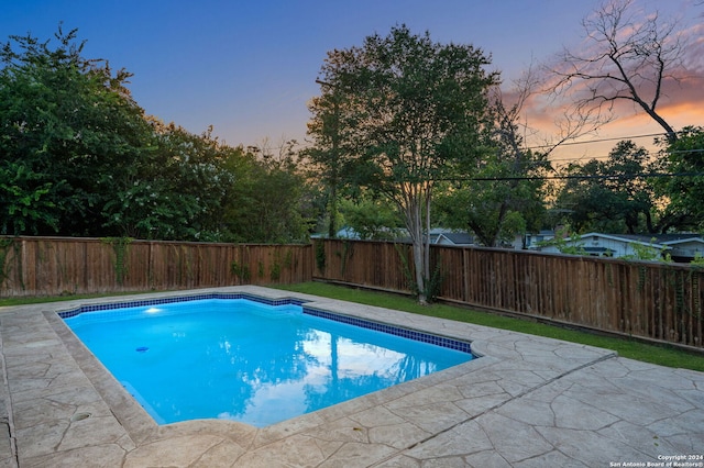 pool at dusk featuring a patio