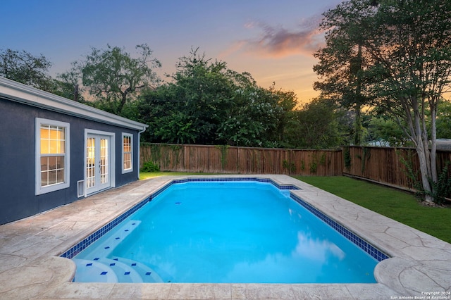 pool at dusk featuring a patio and french doors