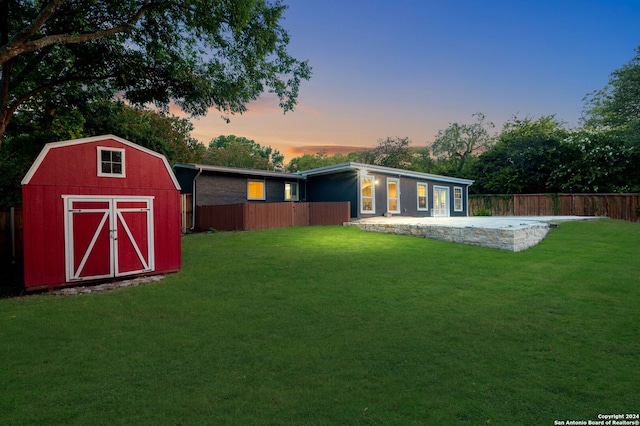 yard at dusk with a storage shed and a patio area