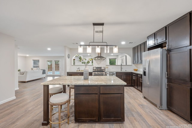 kitchen featuring a kitchen island, appliances with stainless steel finishes, light wood-type flooring, and tasteful backsplash