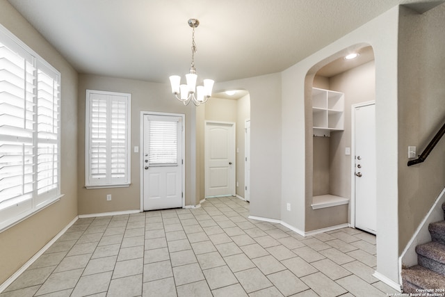 entrance foyer featuring a notable chandelier, light tile floors, and a wealth of natural light