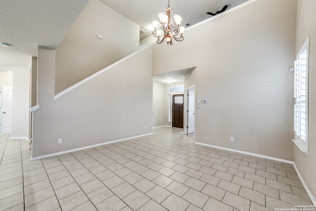 tiled spare room with a chandelier and a towering ceiling