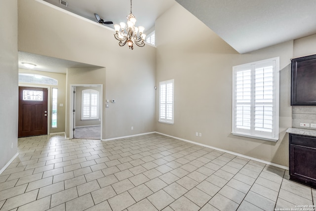 tiled foyer featuring a chandelier, a healthy amount of sunlight, and a high ceiling