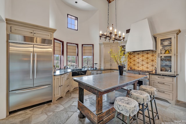 kitchen with backsplash, custom exhaust hood, cream cabinets, and high end appliances