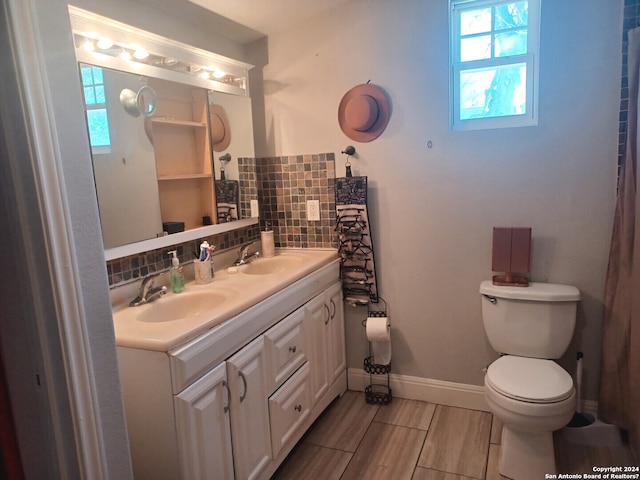 bathroom with backsplash, a wealth of natural light, double vanity, and toilet