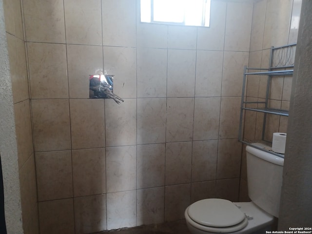 bathroom featuring toilet and tile walls