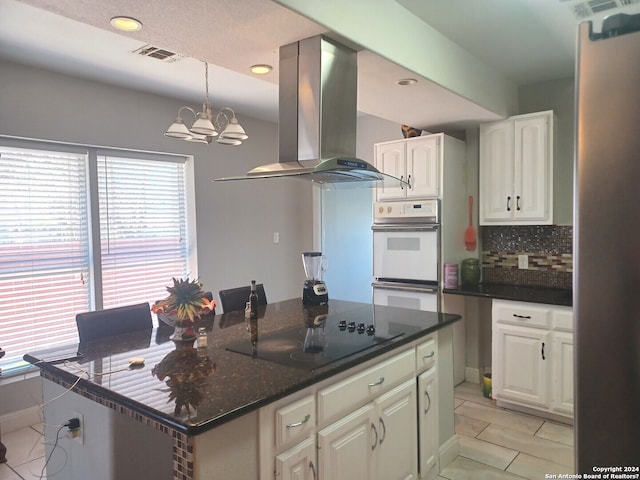 kitchen featuring a chandelier, exhaust hood, tasteful backsplash, white cabinetry, and black electric stovetop