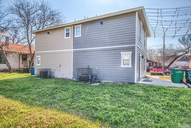 rear view of property featuring a lawn and central AC unit