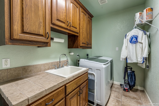 washroom featuring electric dryer hookup, light tile floors, cabinets, independent washer and dryer, and sink