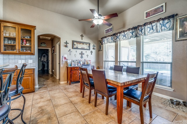 dining room with ceiling fan, light tile floors, and lofted ceiling