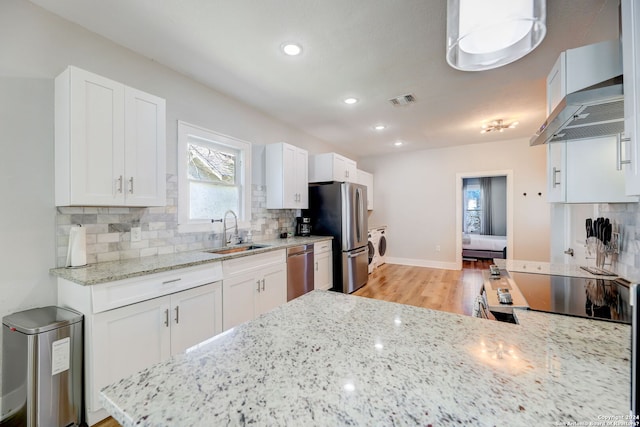 kitchen with light stone countertops, tasteful backsplash, white cabinetry, and wall chimney range hood