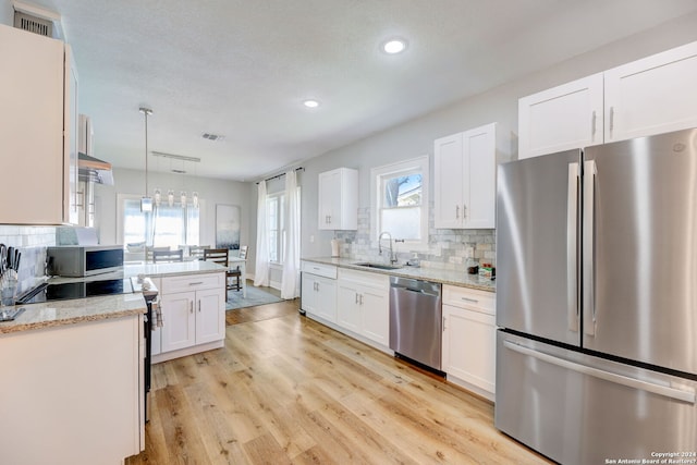 kitchen featuring decorative light fixtures, light hardwood / wood-style floors, a healthy amount of sunlight, and stainless steel appliances