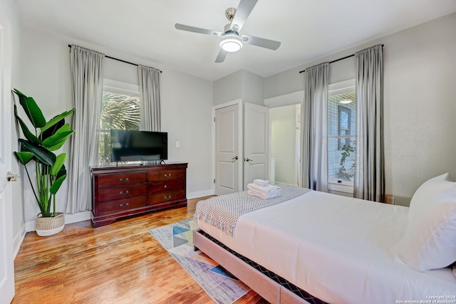 bedroom featuring light wood-type flooring, ceiling fan, and multiple windows