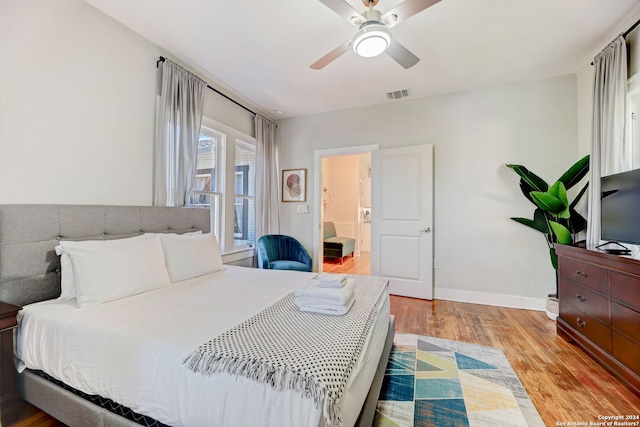 bedroom featuring ensuite bath, ceiling fan, and light wood-type flooring