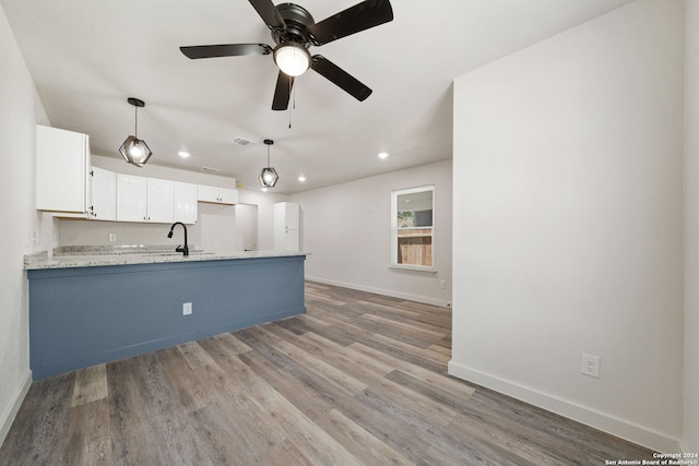 kitchen with pendant lighting, white cabinets, ceiling fan, light stone countertops, and light hardwood / wood-style floors