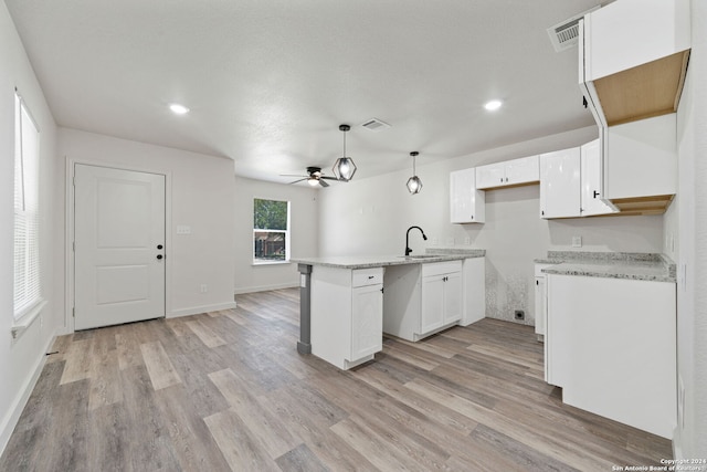 kitchen with ceiling fan, sink, white cabinets, light hardwood / wood-style floors, and hanging light fixtures