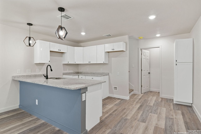 kitchen with white cabinets, kitchen peninsula, hanging light fixtures, and sink